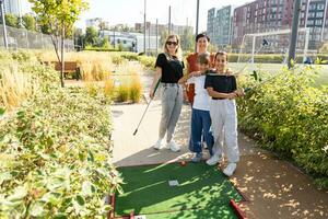 grupo do sorridente amigos desfrutando juntos jogando mini golfe dentro a cidade. foto