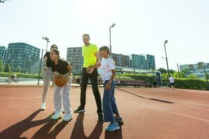 verão feriados, esporte e pessoas conceito feliz família com bola jogando em basquetebol Parque infantil foto