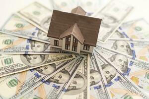 hipoteca conceito. casa e dinheiro. miniatura casa modelo em pilha do dólar nota de banco. foto