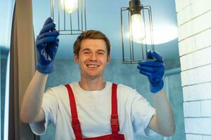 eletricista às trabalhar. serviço para a reparar do elétrico fiação e substituição do teto lâmpadas. uma construtor é instalando uma estilo loft de madeira teto. locatário ajuda com a tarefas domésticas foto