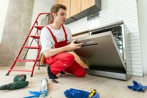 cheio comprimento do reparador reparação lava-louças com Chave de fenda dentro cozinha. foto