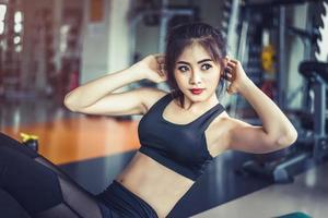 vista lateral da garota asiática fitness fazendo torção crunch no ginásio de fitness. esportes e conceito de treino. ginásio de fitness e tema de beleza