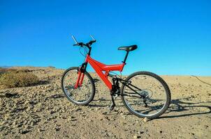 uma vermelho montanha bicicleta é estacionado dentro a deserto foto