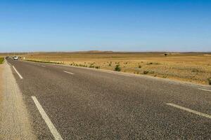uma grandes esvaziar estrada dentro a meio do a deserto foto