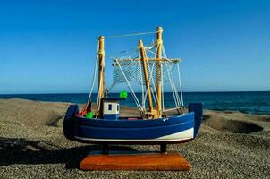 uma brinquedo barco em a de praia perto a oceano foto