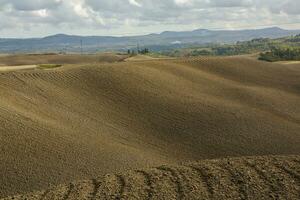 colhido Campos e prados panorama dentro toscana, Itália. ondulado país cenário às outono pôr do sol. arável terra pronto para a agrícola temporada. foto