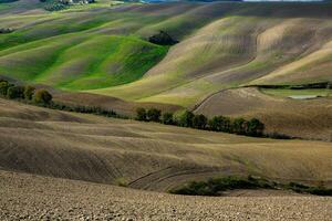 colhido Campos e prados panorama dentro toscana, Itália. ondulado país cenário às outono pôr do sol. arável terra pronto para a agrícola temporada. foto