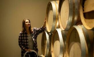 retrato do uma jovem mulher cercado de vinho barris dentro dela adega foto