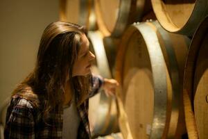 retrato do uma jovem mulher cercado de vinho barris dentro dela adega foto