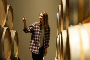 retrato do uma jovem mulher cercado de vinho barris dentro dela adega foto