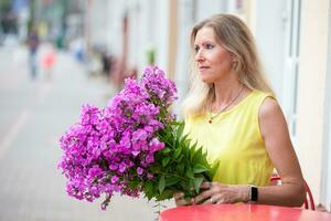 lindo idosos Loiras mulher com uma enorme ramalhete do flores foto