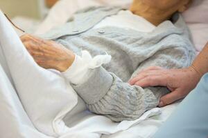 Cuidado para a idosos acamado doente mulher. a mão do uma enfermeira golpes a mão do a idosos enfermo mulher. foto