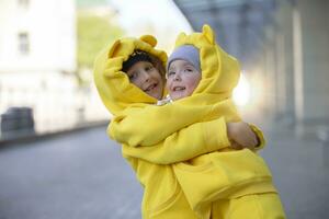 pequeno irmão e irmã. engraçado crianças Garoto e menina dentro amarelo ternos abraço cada outro. foto