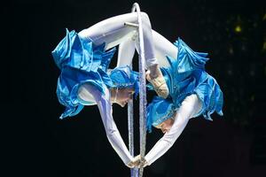 dois acrobata meninas mostrar uma circo número em uma Sombrio fundo. acrobático desempenho. foto