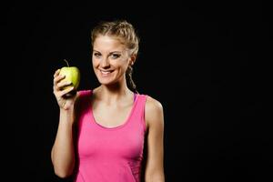 lindo desportivo mulher segurando maçã em fundo preto foto