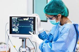 médica apontando para o monitor de freqüência cardíaca na operação room.healthcare e conceito médico. hospital e tema de pessoas foto