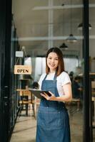 comece bem sucedido pequeno o negócio proprietário sme mulher ficar de pé com tábua dentro cafeteria restaurante. mulher barista foto