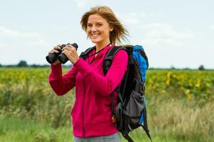 mulher caminhante com binóculos dentro natureza foto