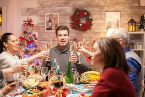 grande família às Natal família jantar brindar com branco vinho. delicioso Comida. foto