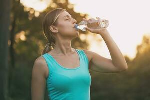 lindo mulher goza bebendo água durante exercício.toned imagem. foto