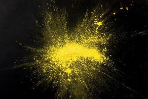 explosão de pó de cor amarela na superfície preta foto