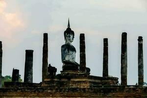 uma ampla estátua do Buda sentado dentro a meio do uma ampla grupo do pilares foto