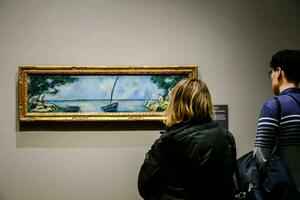 dois pessoas olhando às uma pintura do uma barco em uma lago foto