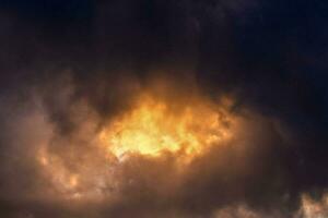 uma Sombrio nuvem com uma brilhante amarelo luz chegando através foto
