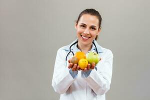 lindo fêmea médico é mostrando fruta. foto