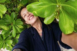 engraçado sorridente mulher levando selfies entre tropical folhas. foto