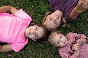 vista superior de três meninas rindo enquanto deitavam na grama do lado de fora foto