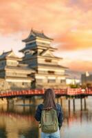 mulher turista visitando dentro matsumoto, feliz viajante passeios turísticos Matsumoto castelo ou Corvo castelo. ponto de referência e popular para turistas atração dentro matsumoto, Nagano, Japão. viagem e período de férias conceito foto