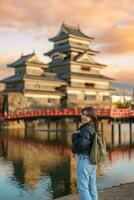 mulher turista visitando dentro matsumoto, feliz viajante passeios turísticos Matsumoto castelo ou Corvo castelo. ponto de referência e popular para turistas atração dentro matsumoto, Nagano, Japão. viagem e período de férias conceito foto