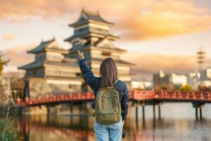 mulher turista visitando dentro matsumoto, feliz viajante passeios turísticos Matsumoto castelo ou Corvo castelo. ponto de referência e popular para turistas atração dentro matsumoto, Nagano, Japão. viagem e período de férias conceito foto