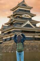 mulher turista visitando dentro matsumoto, feliz viajante passeios turísticos Matsumoto castelo ou Corvo castelo. ponto de referência e popular para turistas atração dentro matsumoto, Nagano, Japão. viagem e período de férias conceito foto