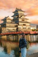 mulher turista visitando dentro matsumoto, feliz viajante passeios turísticos Matsumoto castelo ou Corvo castelo. ponto de referência e popular para turistas atração dentro matsumoto, Nagano, Japão. viagem e período de férias conceito foto