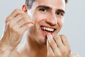 jovem homem usando dental fio dental foto