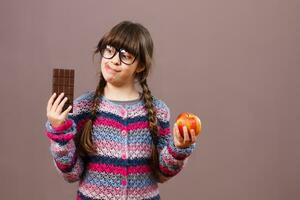 pequeno nerd menina seria em vez de comer chocolate então fruta foto