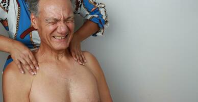 Mais velho maduro homem tendo uma massagem em dele superior costas e pescoço para dor alívio foto