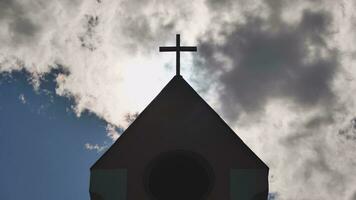 a silhueta do uma católico Igreja torre contra uma fundo do Sol e nuvens. foto