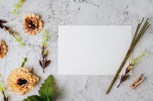 um cartão em branco e uma flor são colocados em um fundo branco foto