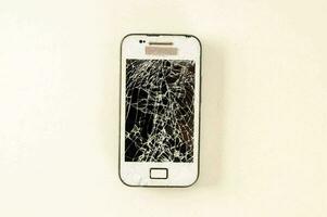 uma quebrado célula telefone sentado em uma branco superfície foto