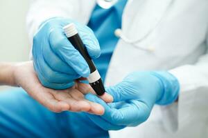 ásia médico usando lanceta caneta em Senior paciente dedo para Verifica amostra sangue açúcar nível para tratamento diabetes. foto