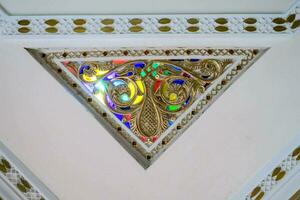 uma decorativo triângulo com colorida vidro em a teto foto