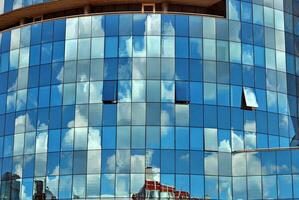 vidro construção com transparente fachada do a construção e azul céu. estrutural vidro parede refletindo azul céu. abstrato moderno arquitetura fragmento. contemporâneo arquitetônico fundo. foto