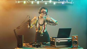 disco jóquei dá polegares acima enquanto mistura música às techno festa, criando funky atmosfera em etapa às clube. mulher dj usando graves ao controle botões e estéreo equipamento para remix. tripé tomada. foto