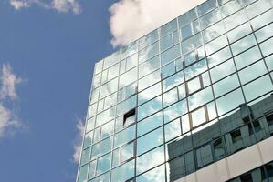 vidro construção com transparente fachada do a construção e azul céu. estrutural vidro parede refletindo azul céu. abstrato moderno arquitetura fragmento. contemporâneo arquitetônico fundo. foto