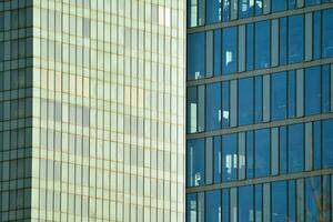 vidro construção com transparente fachada do a construção e azul céu. estrutural vidro parede refletindo azul céu. abstrato moderno arquitetura fragmento. contemporâneo arquitetônico fundo. foto