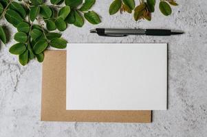 um cartão em branco com envelope, caneta e folha é colocado no fundo branco foto