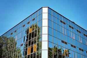 vidro construção com transparente fachada do a construção e azul céu. estrutural vidro parede refletindo azul céu. abstrato moderno arquitetura fragmento. contemporâneo arquitetônico fundo. foto